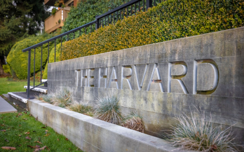 An engraved sign on concrete on the outside of the building that has "The Harvard" engraved into it