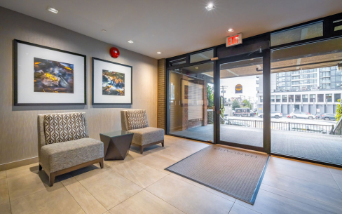 Front interior lobby of The Harvard with two lounge chairs and a small coffee table in between. The photo is angled to look out St. Georges Avenue